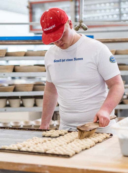 Bäcker von Sailer bestreicht traditionellen Zopf mit Besen